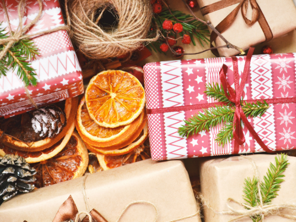 Wrapped Christmas presents, pine sprigs, and orange slices decorate a festive spread of holiday treats and boxes.