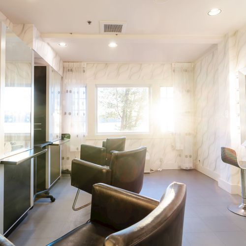 A stylish, modern hair salon with white marble walls, black chairs, mirrors, and a bright window-lit styling area. Top it at 140 characters, always ending the sentence.