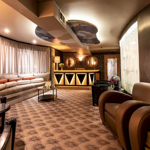 A retro lounge with brown seating, a long curved sofa, patterned carpet, dim lighting, curtained windows, and a bar area in the back, cozy yet stylish.