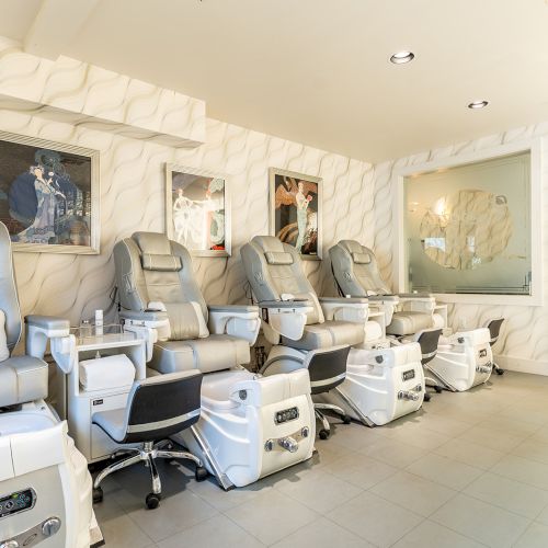 A modern nail or spa clinic with row of pedicure chairs and foot baths, clean bright space and minimalist decor, white/gray tones.