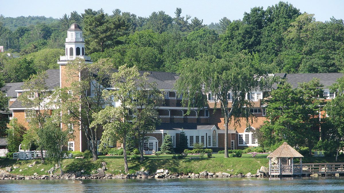 A serene lakeside building with a bell tower, surrounded by greenery and water, offers a picturesque, peaceful setting amidst nature's beauty.