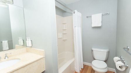 This is a modern bathroom with a bathtub/shower, toilet, sink, towel rack, and light wood flooring.