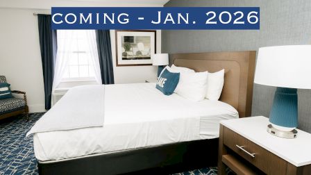A hotel room with a bed, lamps, and a modern design. Text overlay reads "Coming - Jan. 2026."
