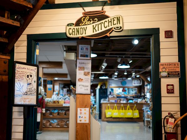The image shows the entrance to a shop called "Lee's Candy Kitchen" with various signs and posters on the door, and colorful items inside.