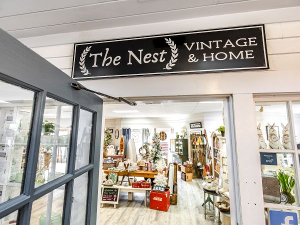 A shop named "The Nest VINTAGE & HOME" with rustic decor, furniture, and various vintage items displayed inside.