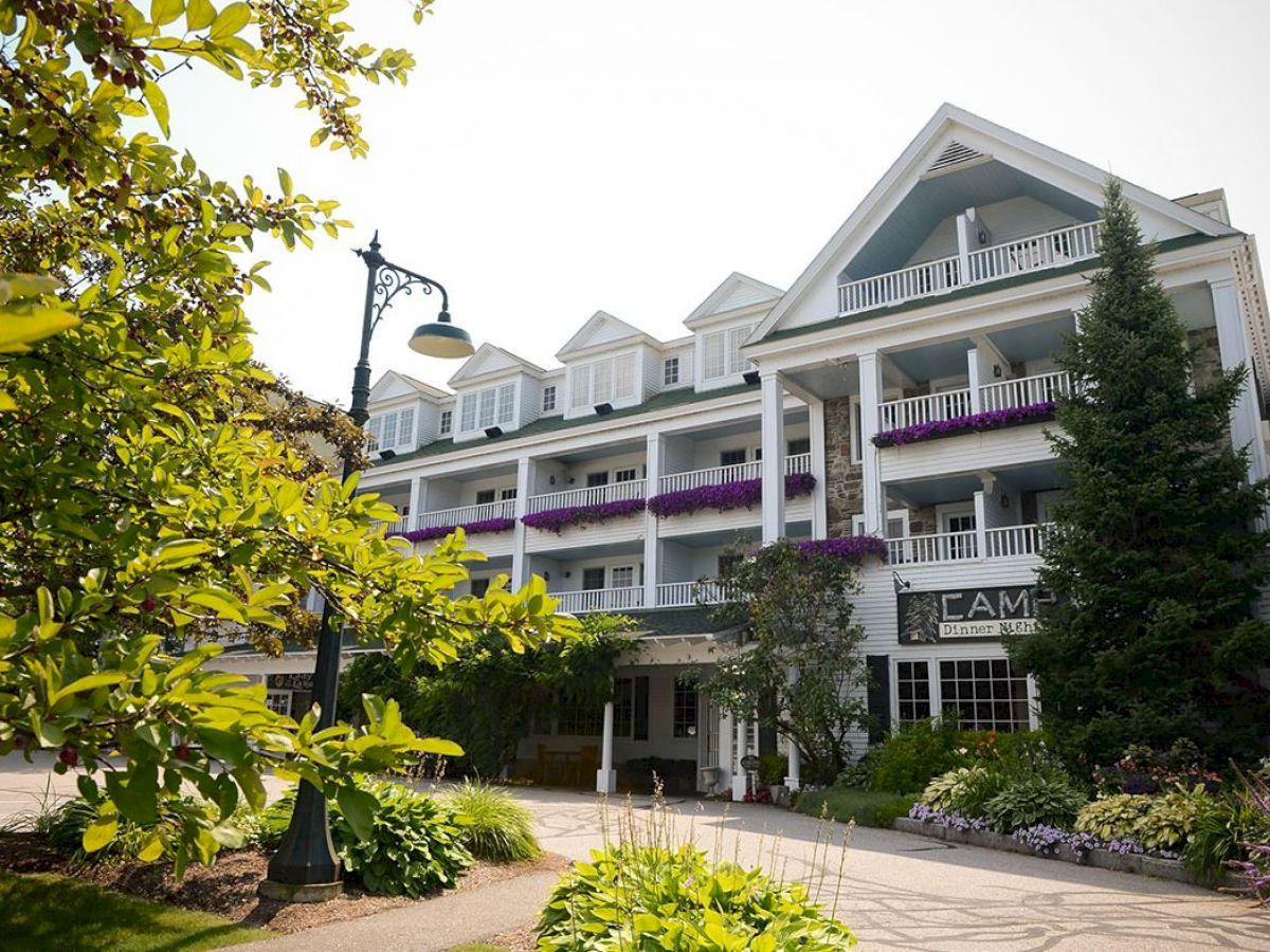 This image shows a charming multi-story building with balconies, surrounded by greenery and flowers, and featuring an ornate streetlamp.