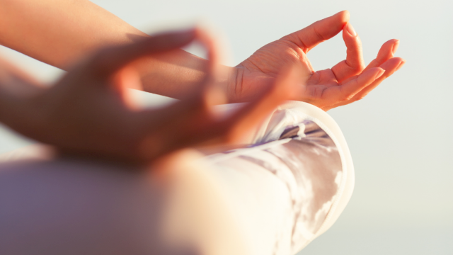 People meditating outdoors, hands resting in a mudra on a yoga mat, a calm, scenic backdrop and soft natural light.