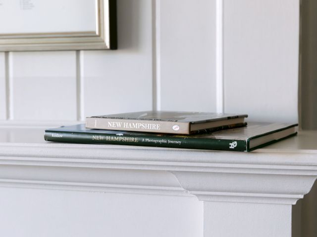 The image shows two books stacked on a white shelf, with one titled "New Hampshire" and another being a photography book.