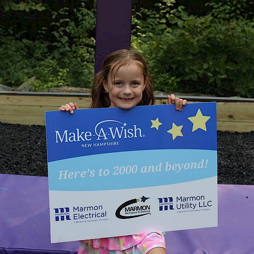 A smiling child holds a "Make-A-Wish New Hampshire" sign, indicating support from Marmon Electrical and Marmon Utility LLC.
