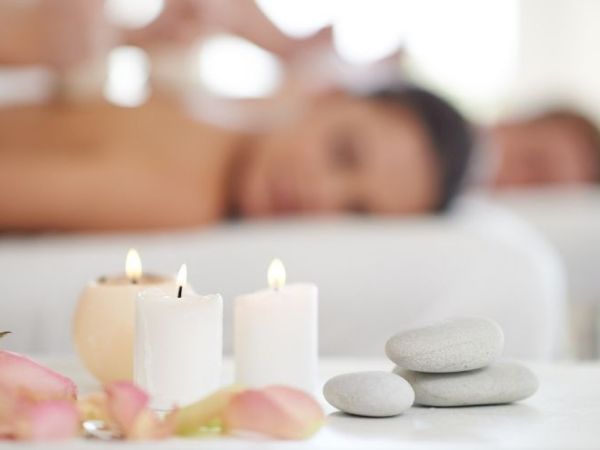 A relaxing spa scene with lit candles, smooth stones, and blurred figures receiving massages in the background, adding to the serene ambiance.