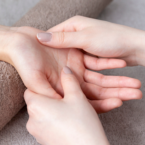 A person gives a hand massage or acupressure on the wrist with a roller or finger pressure, soothing care for a calm moment.