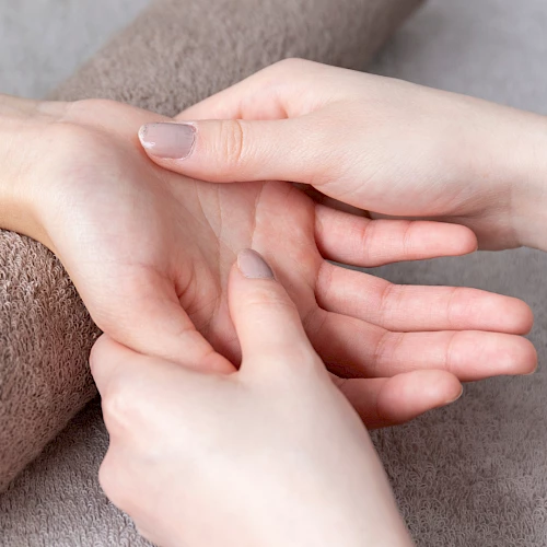 A person gives a hand massage or acupressure on the wrist with a roller or finger pressure, soothing care for a calm moment.