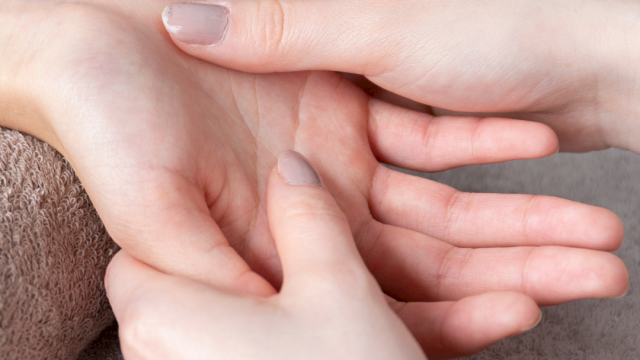 A person gives a hand massage or acupressure on the wrist with a roller or finger pressure, soothing care for a calm moment.