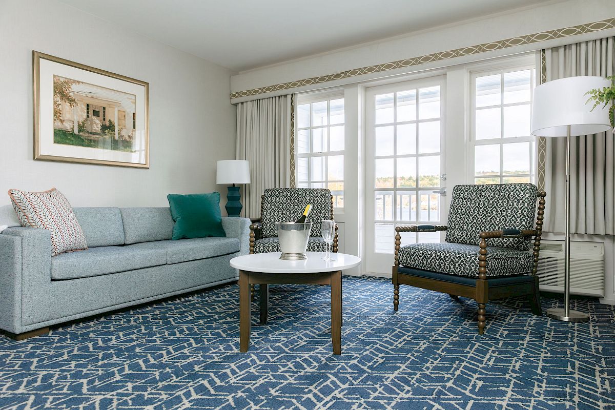 A modern living room with a sofa, two chairs, a coffee table with a bottle, a floor lamp, and large windows with curtains ends the sentence.