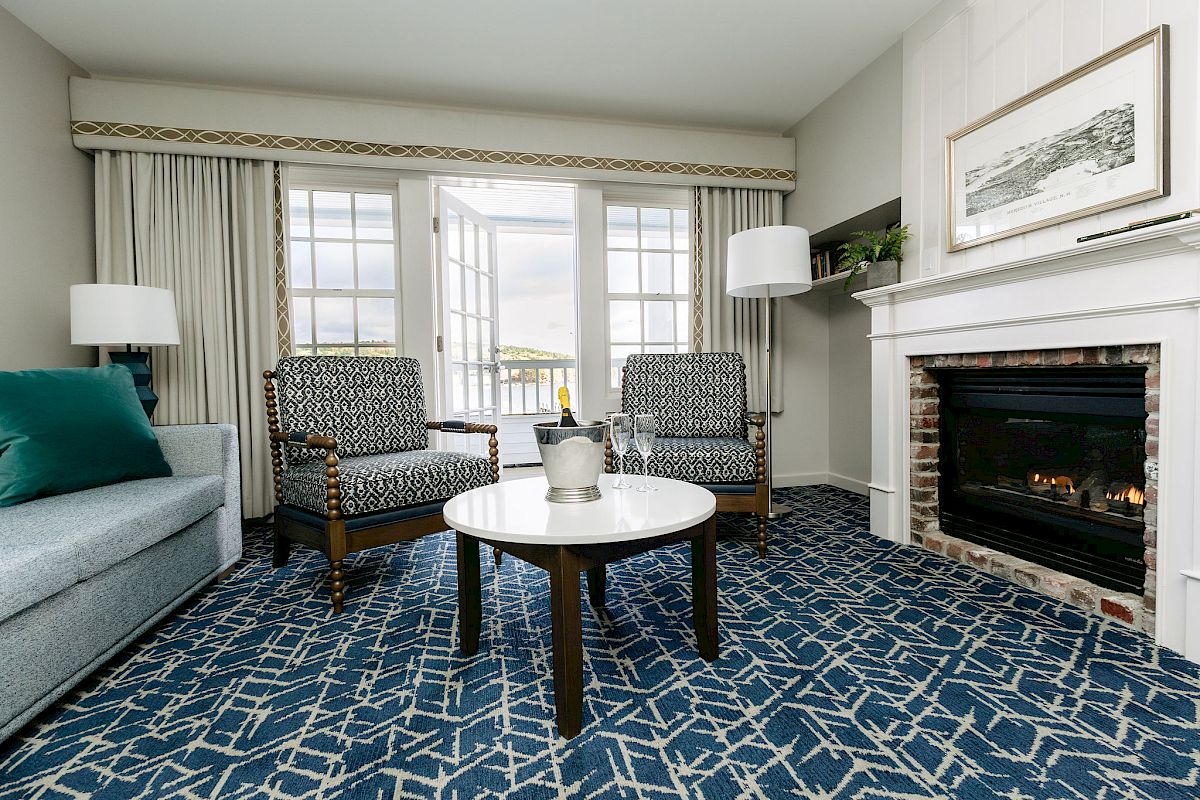 A cozy living room with two armchairs, a sofa, coffee table, fireplace, large window, and decorative elements.