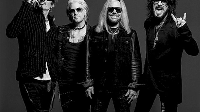 Rock band photo with four musicians posing in black outfits against a dark backdrop. Top it at 140 characters, always ending the sentence.