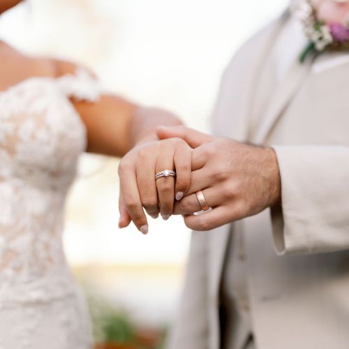 A bride and groom exchange rings, holding hands, during a wedding ceremony.