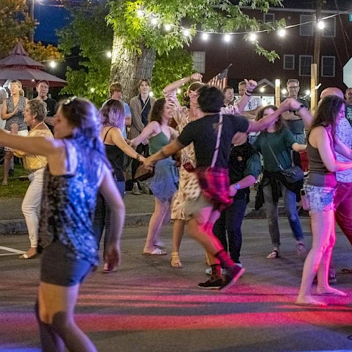 A lively outdoor dance party with people twirling, swapping partners, and enjoying string lights under a night market vibe.
