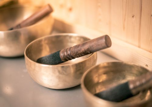 A set of Tibetan singing bowls with wooden mallets resting inside, arranged on a smooth surface.