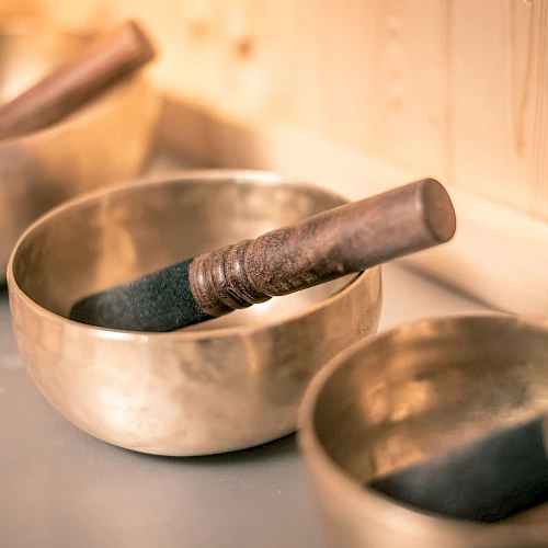 A set of Tibetan singing bowls with wooden mallets resting inside, arranged on a smooth surface.