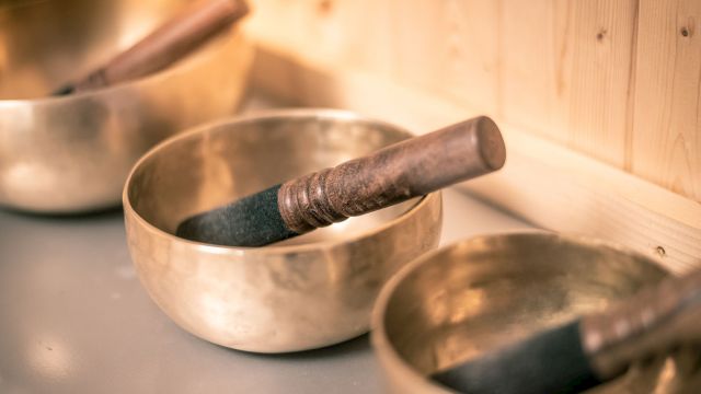 A set of Tibetan singing bowls with wooden mallets resting inside, arranged on a smooth surface.