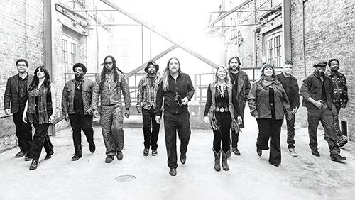 A group of people walking confidently down a snowy alley, leather jackets and casual wear, urban vibe, black‑and‑white photo.