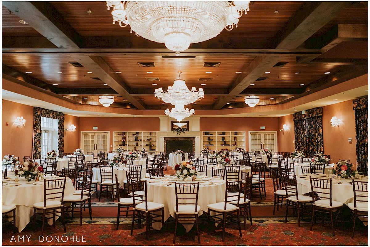 Elegant banquet hall with round tables, white linens, and chandeliers, ready for a formal wedding or reception.